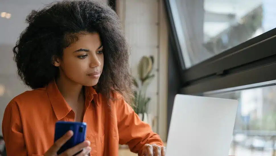 Black woman working on laptop near a window