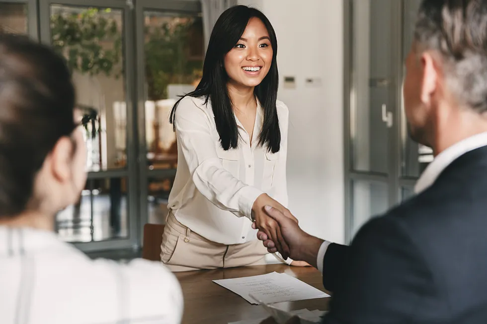 Young and confident Asian woman shaking hands with man in an office